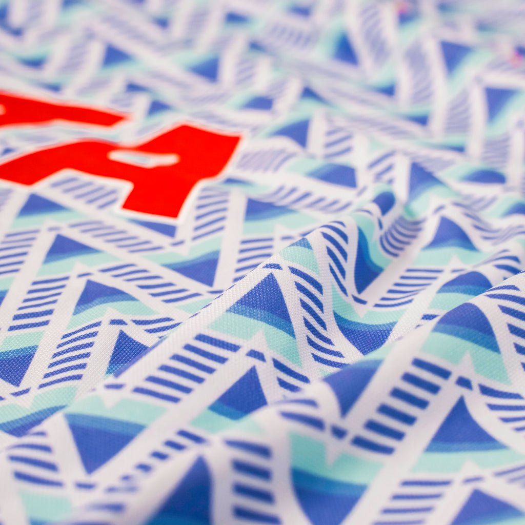 Sky Blue 90 Polo close-up showing blue and aqua geometric fabric and red PATA logo.