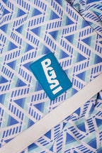 Sky Blue 90 Polo sleeve close-up showing the blue PGS patch, geometric print, and white cuff.